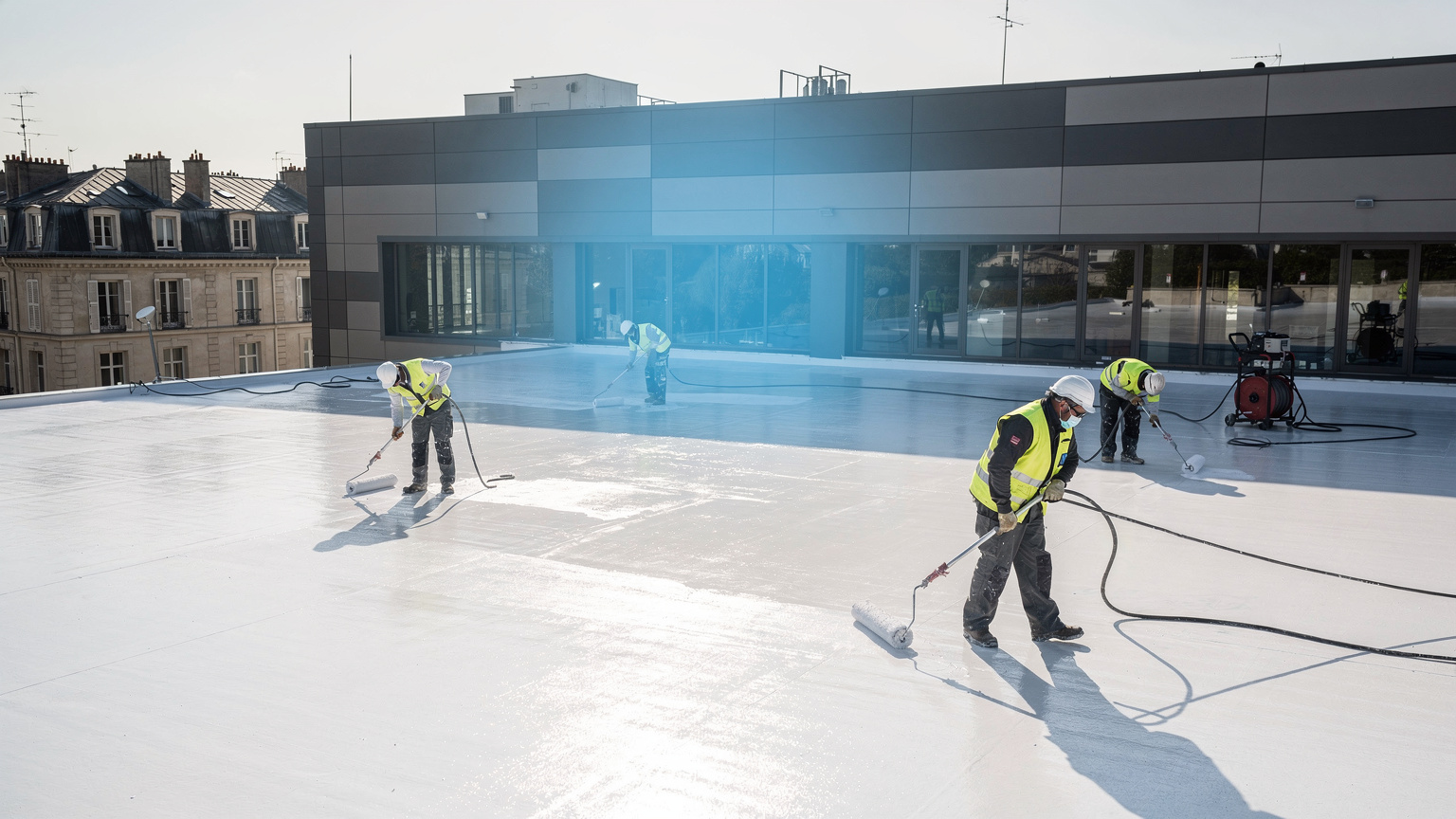 Application de peinture cool roof blanche sur une toiture professionnelle pour réduire la chaleur et améliorer l’efficacité énergétique